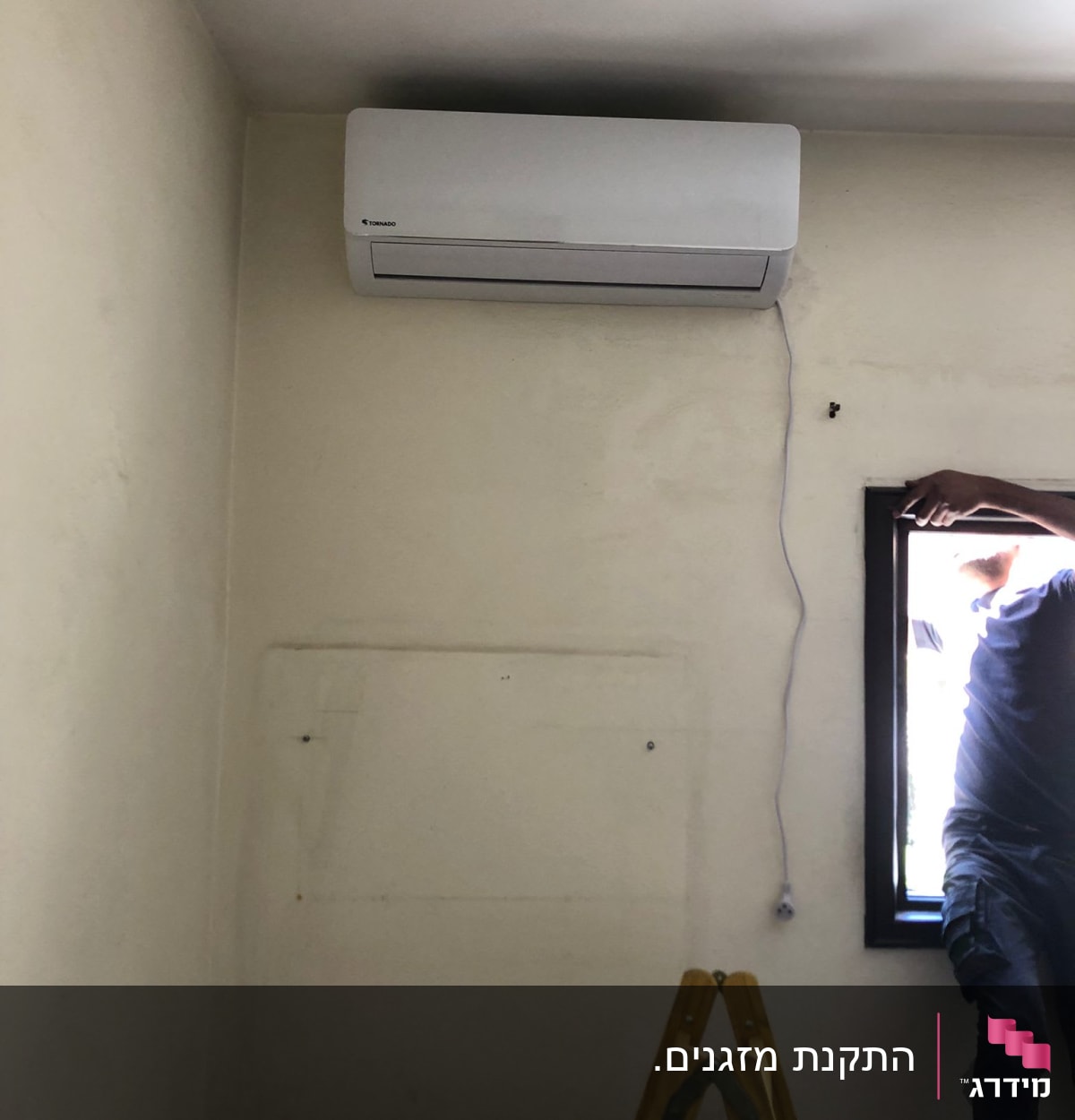 מזגן מותקן על קיר עם כבל חשמל מחובר